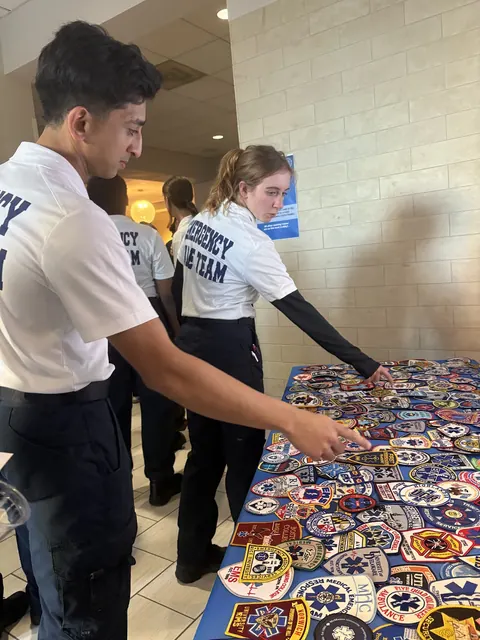 Two team members in white uniform shirts looking over a table covered with colorful patches.