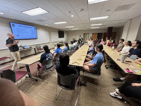 A classroom full of students listening to an instructor at the front during a suture clinic.